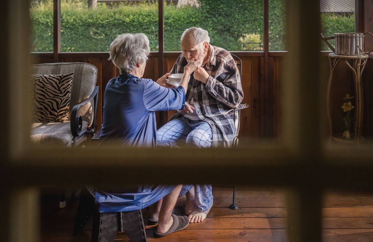 A caregiver helping to feed their loved one with dementia. Next Avenue, aphasia, language