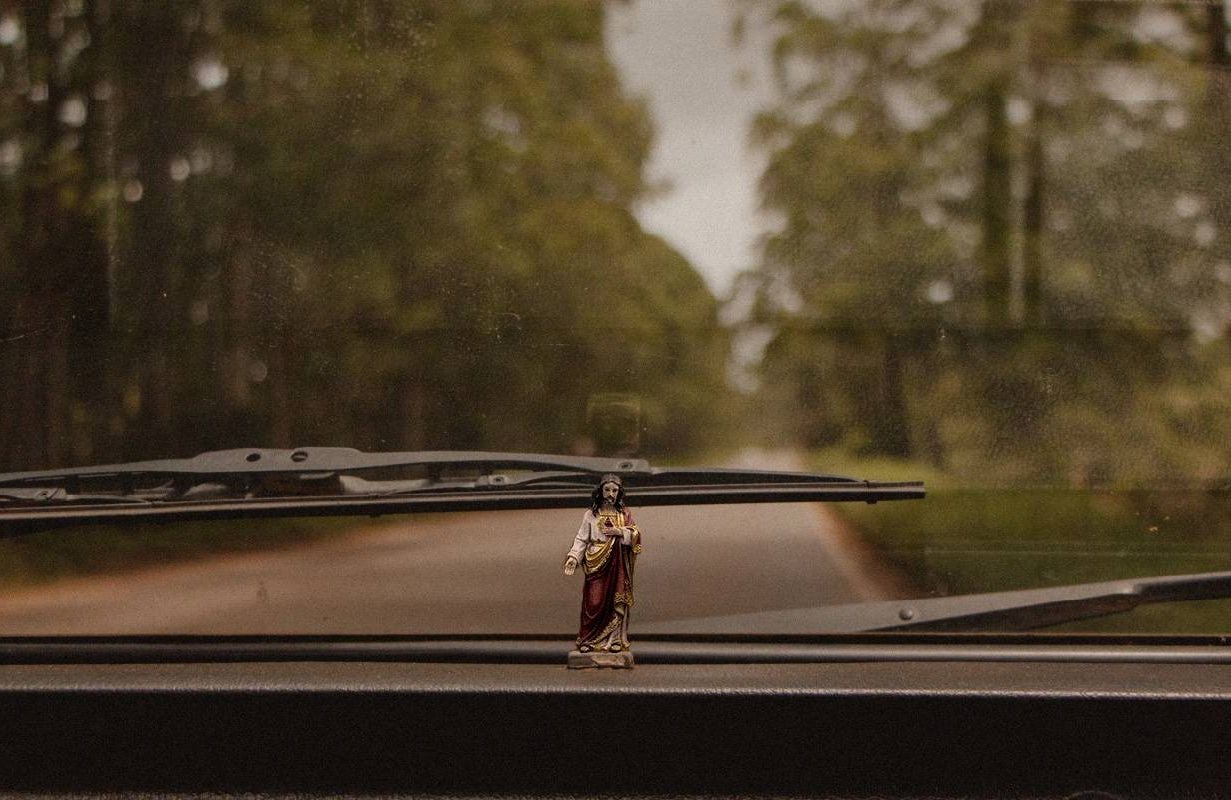 A small jesus figurine on a car's dashboard. Next Avenue, religion