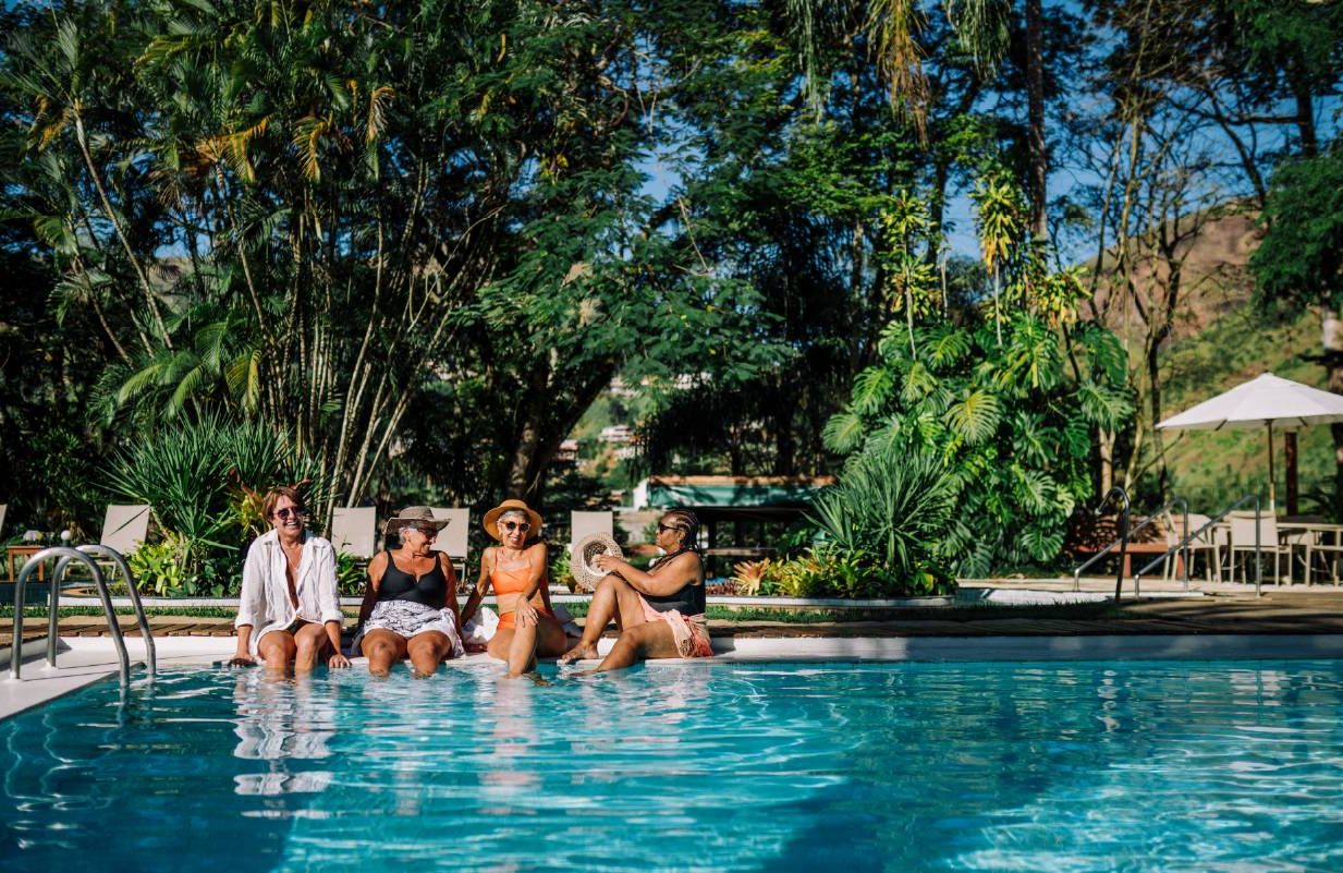 A group of older women on a trip sitting by the pool. Next Avenue, planning a group trip