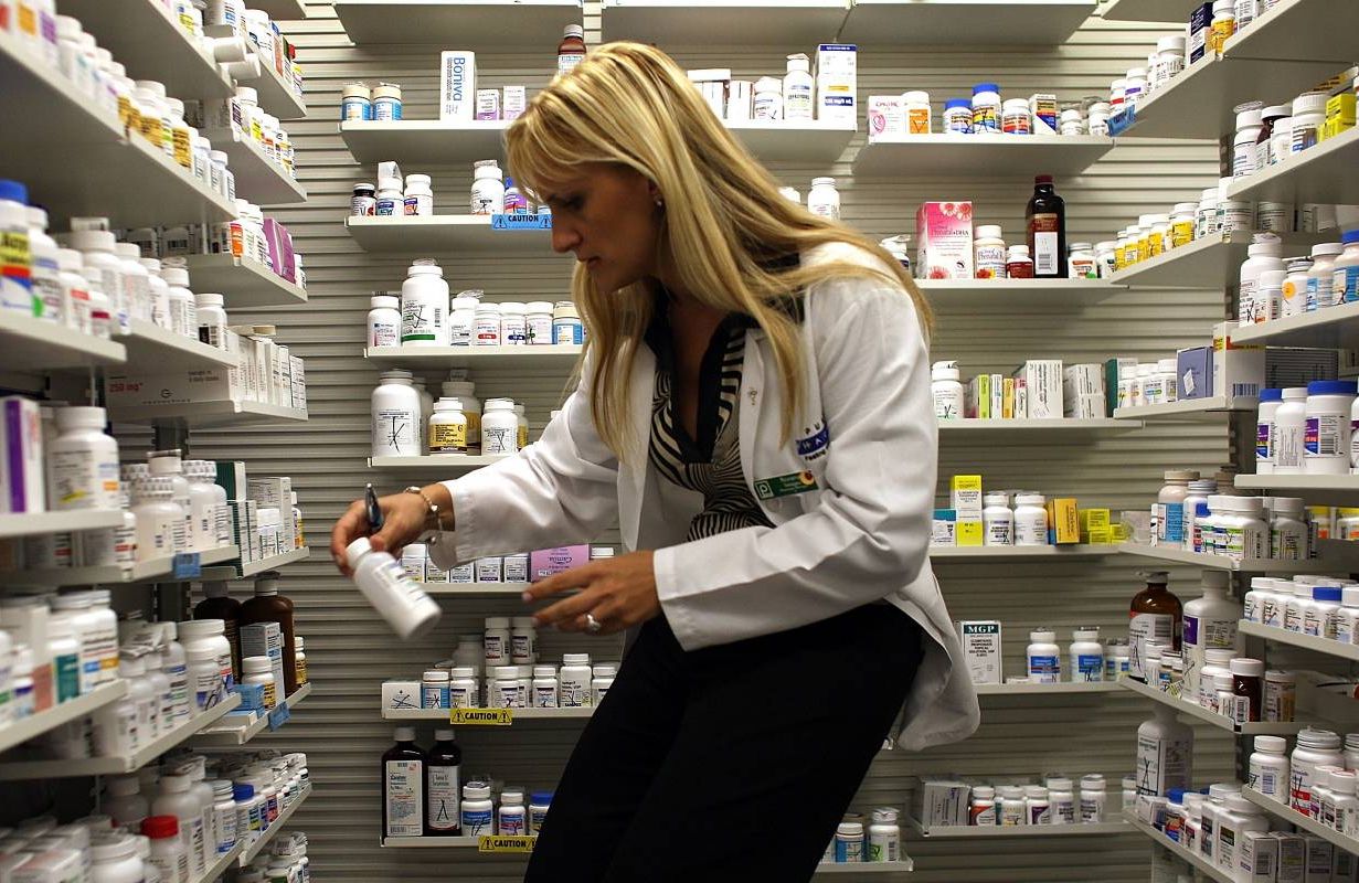 A pharmacist reading the labels of various drugs. Next Avenue,