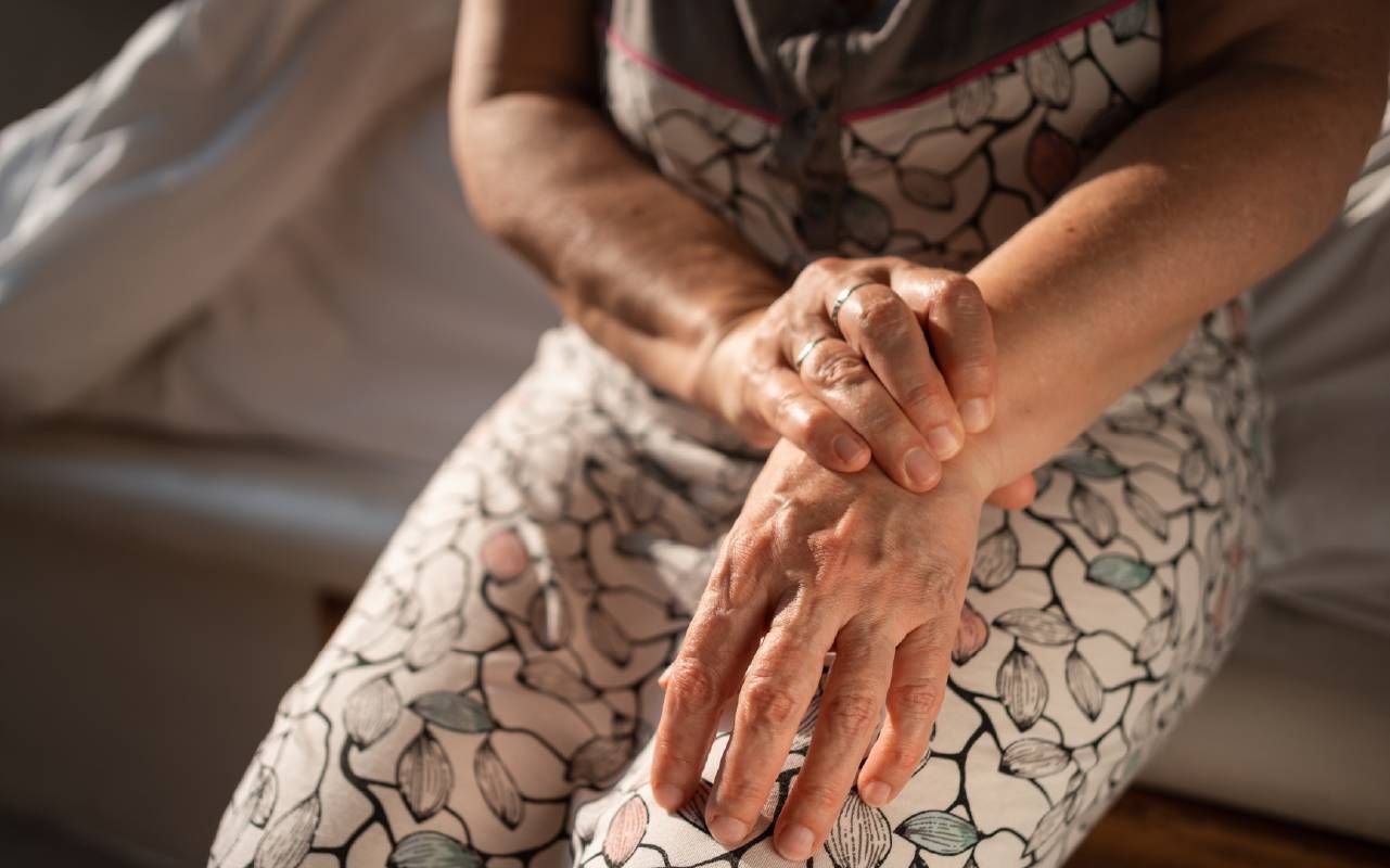 A woman massaging her wrists after dealing with Rheumatoid Arthritis pain. Next Avenue