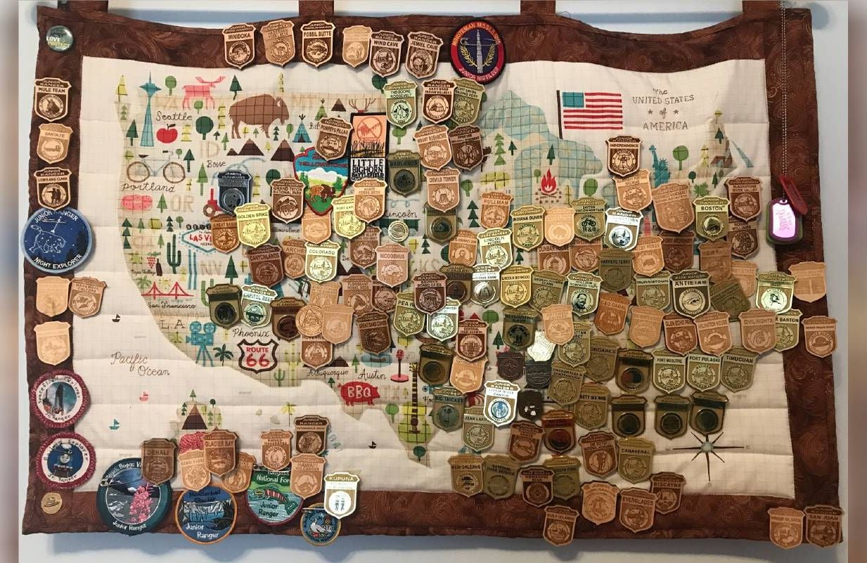A quilted wall hanging with many small pins. Next Avenue, stuff, downsizing, collecting