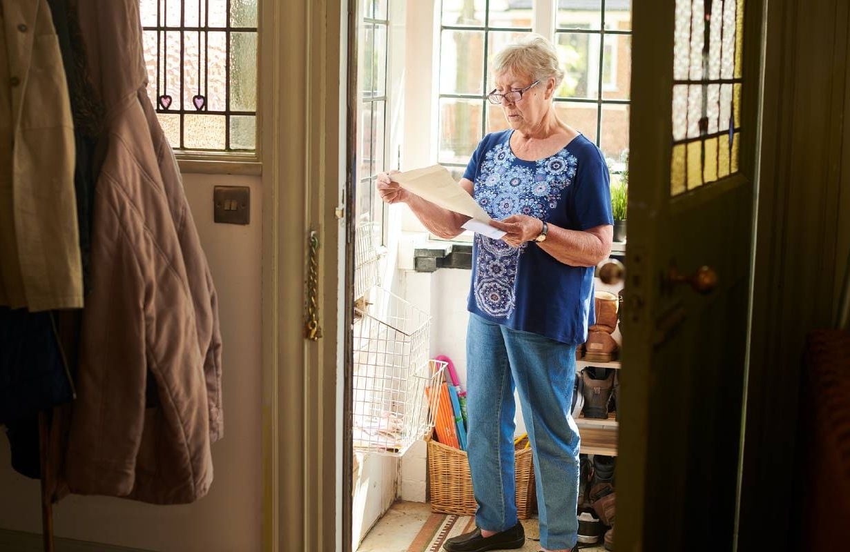 Woman reading a letter in the mail. Next Avenue, debt, what to do, help with debt