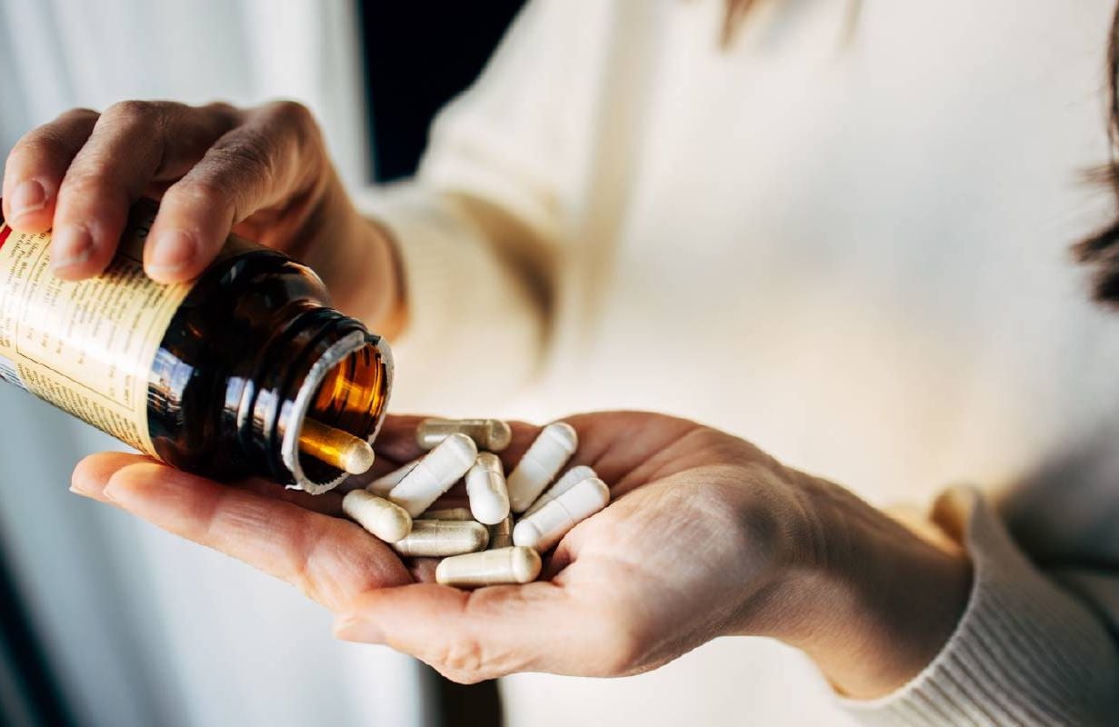 A person holding multiple vitamins. Next Avenue, health benefits