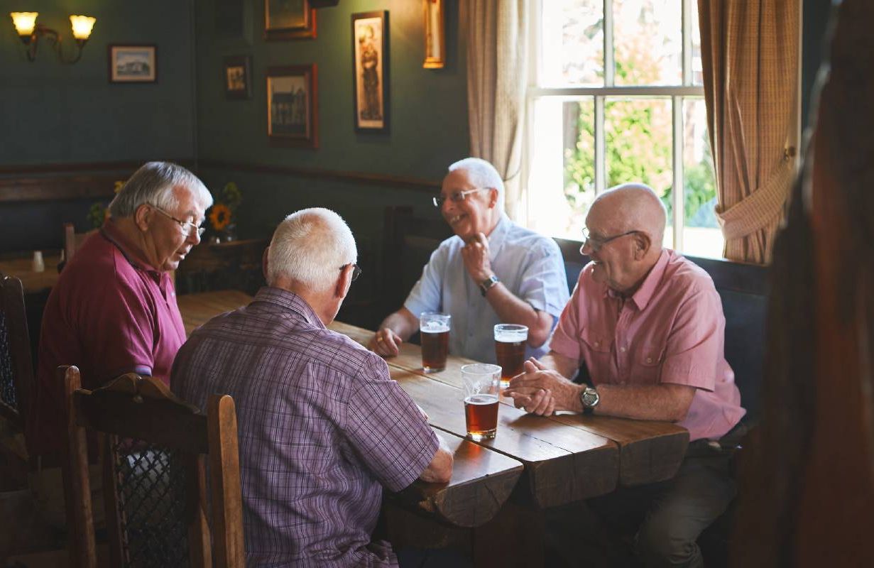 Group of older men sitting together in a bar. Next Avenue, fantasy baseball