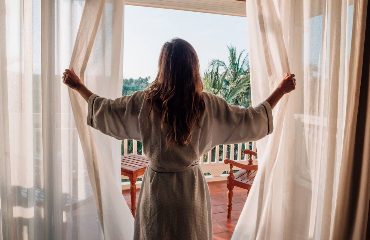 A person opening the cutains. Next Avenue, sleep tourism