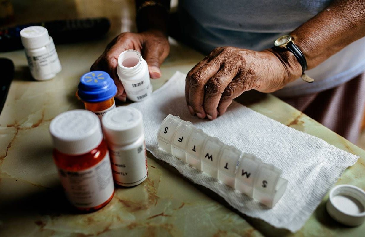 A person putting their prescription medication in a pill box. Next Avenue, Tariffs on Prescription Drugs