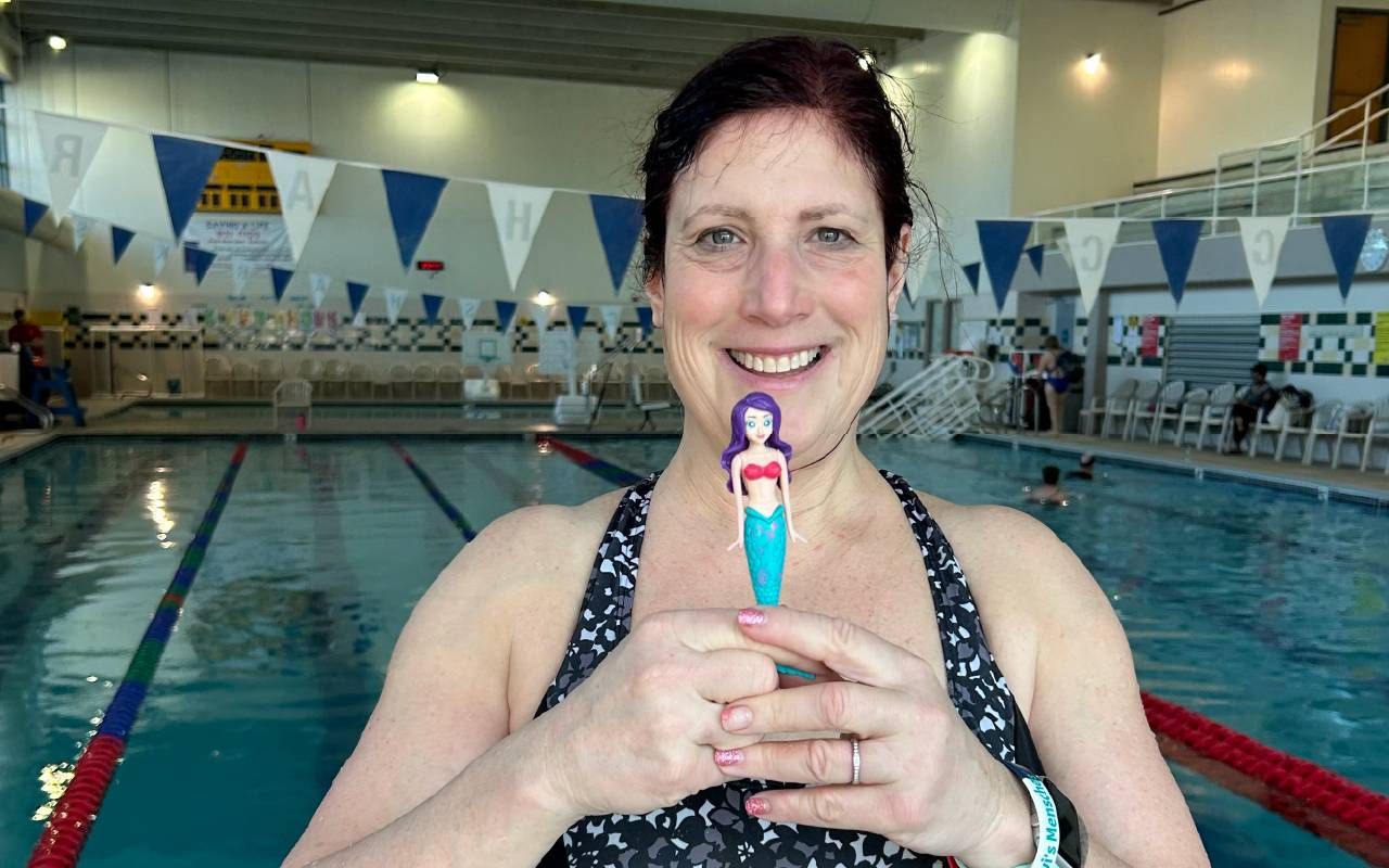 A woman holding a mermaid figurine at a pool. Next Avenue, grief, loss,