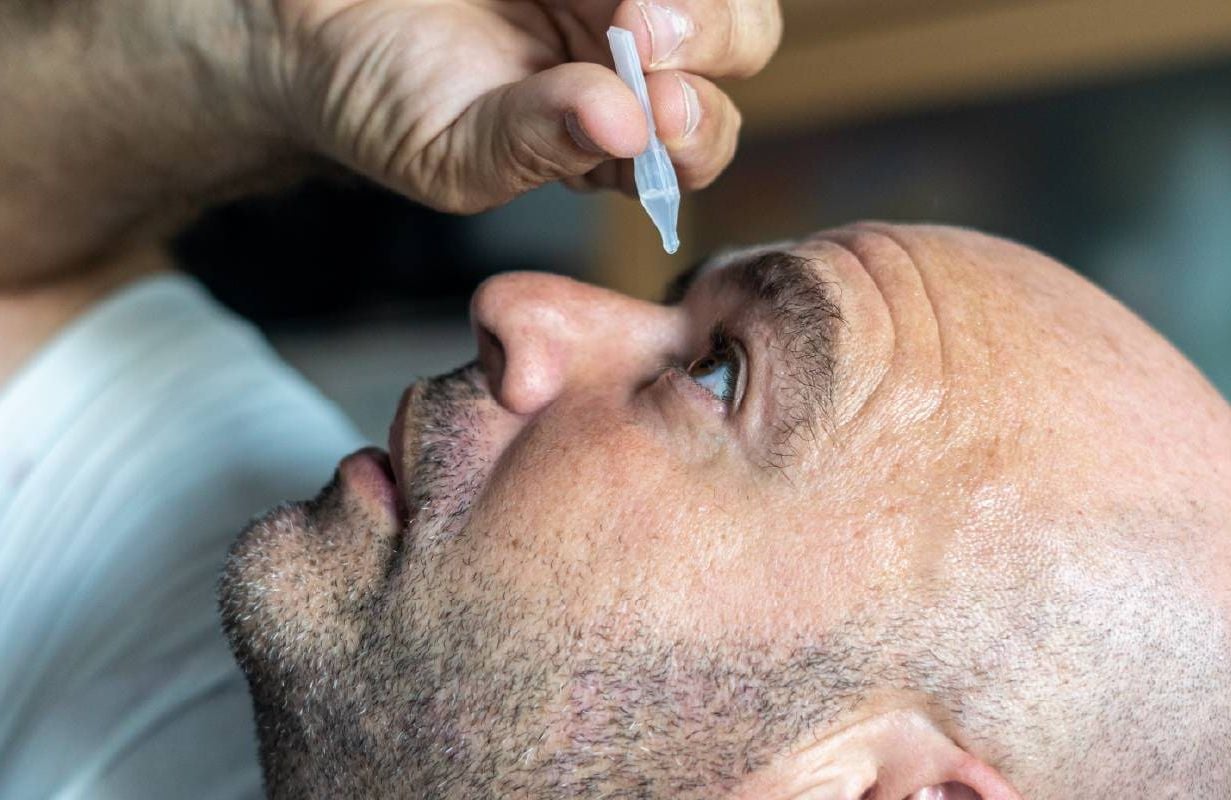 A person putting eye drops in their eye. Next Avenue, dry eye disease