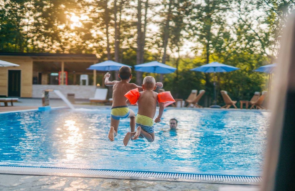 Two young boys jumping and splashing in a pool. Next Avenue, grandchildren visiting