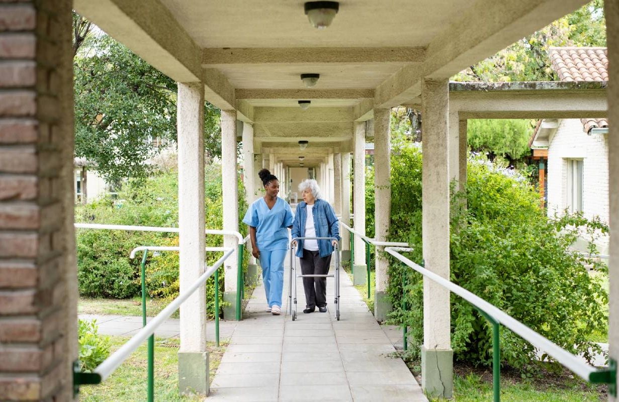 A woman in an assisted living home walking outside. Next Avenue