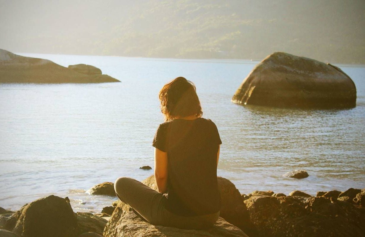 A person meditating near a lake. Next Avenue, minfulness meditation