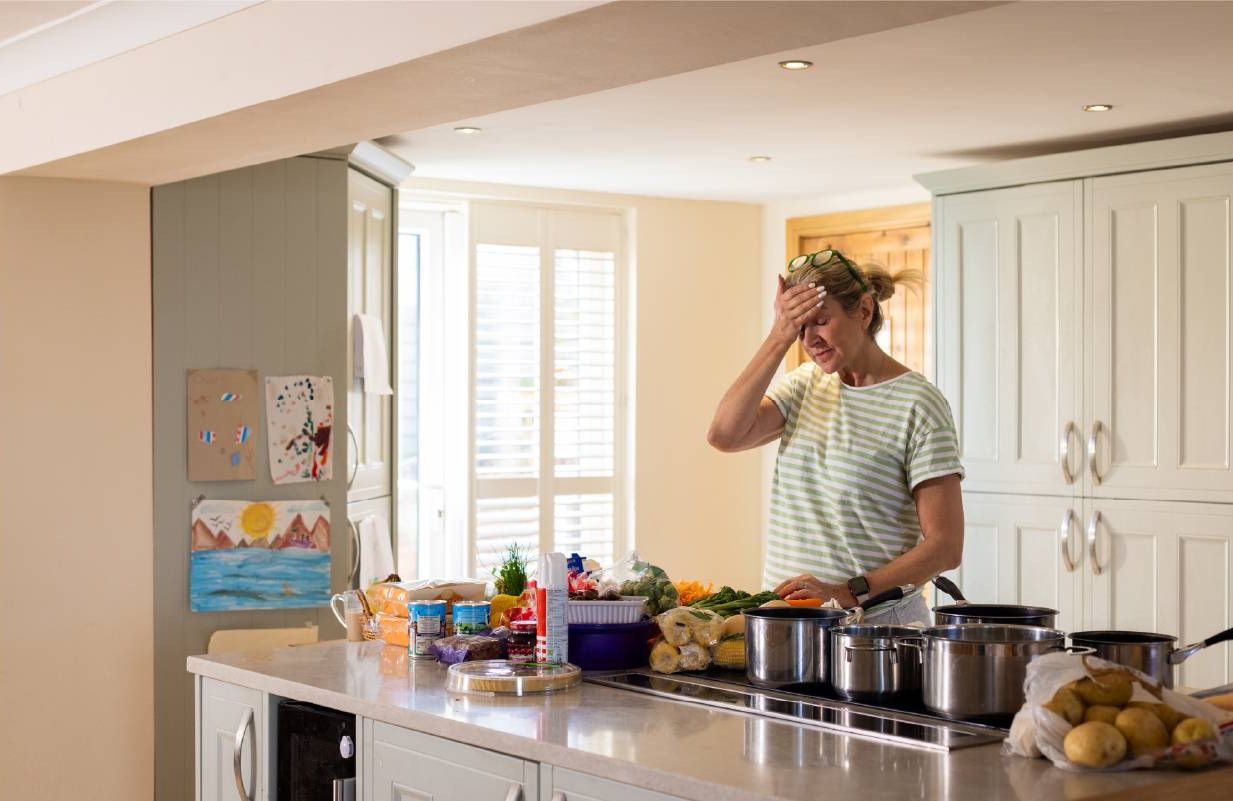 A woman looking frustrated at home in the kitchen. Next Avenue, clumsy