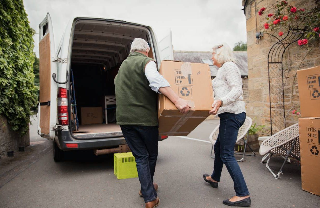 Older adults moving boxes into a moving truck. Next Avenue, downsizing