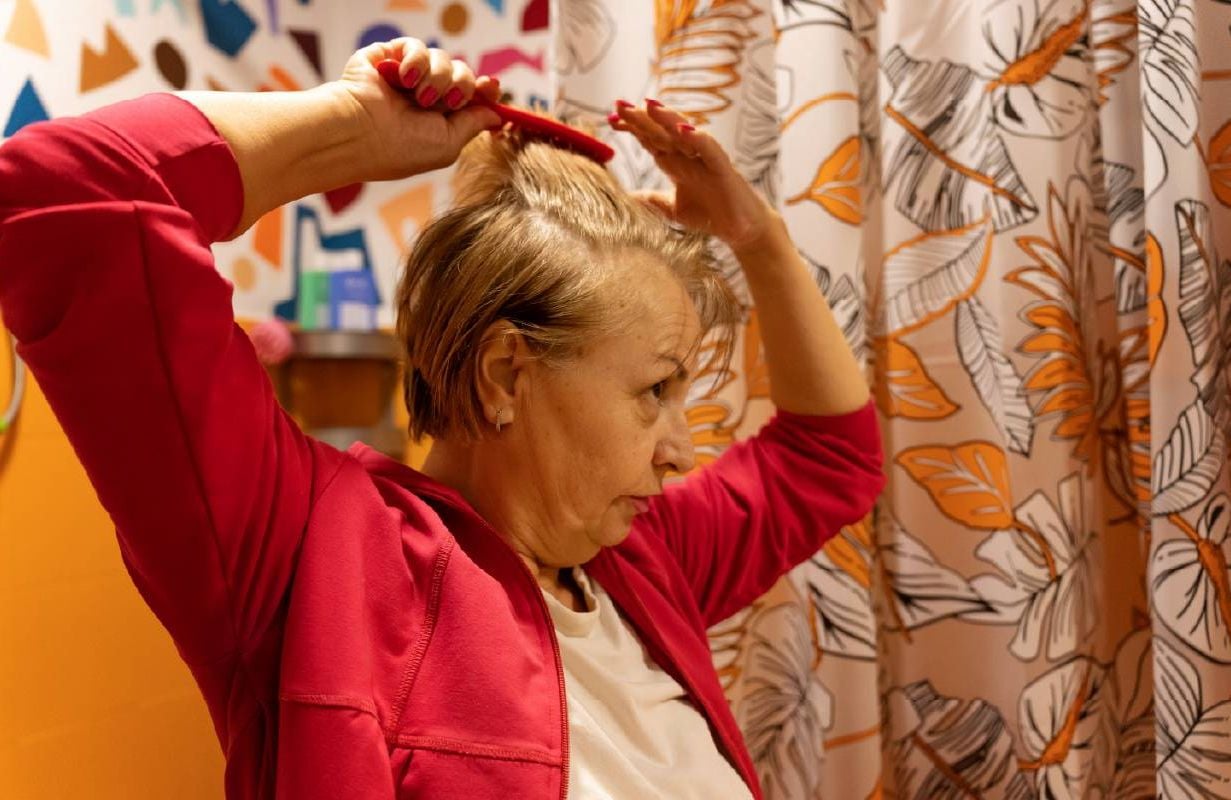 A middle aged woman brushing her hair. Next Avenue, hairloss
