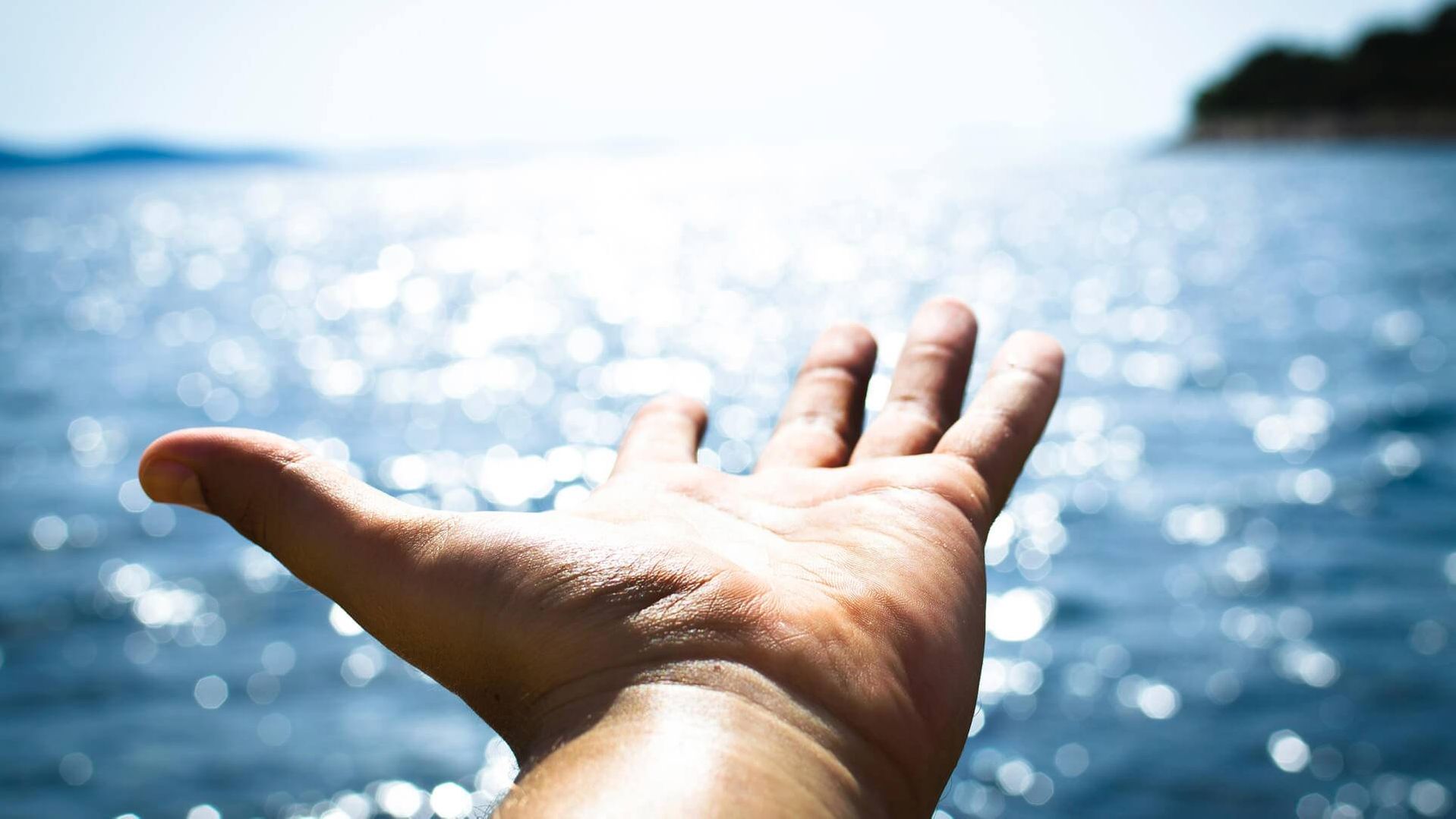 Outstretched hand over glistening lake