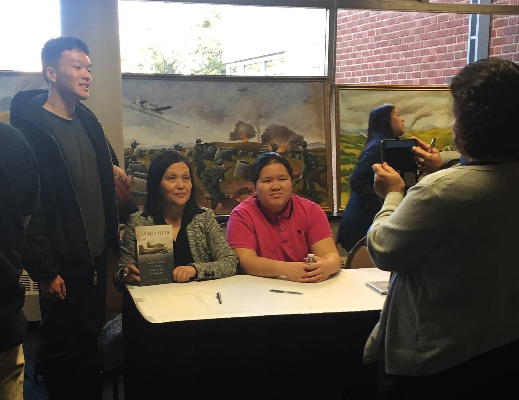 Young adults pose with female Hmong book author