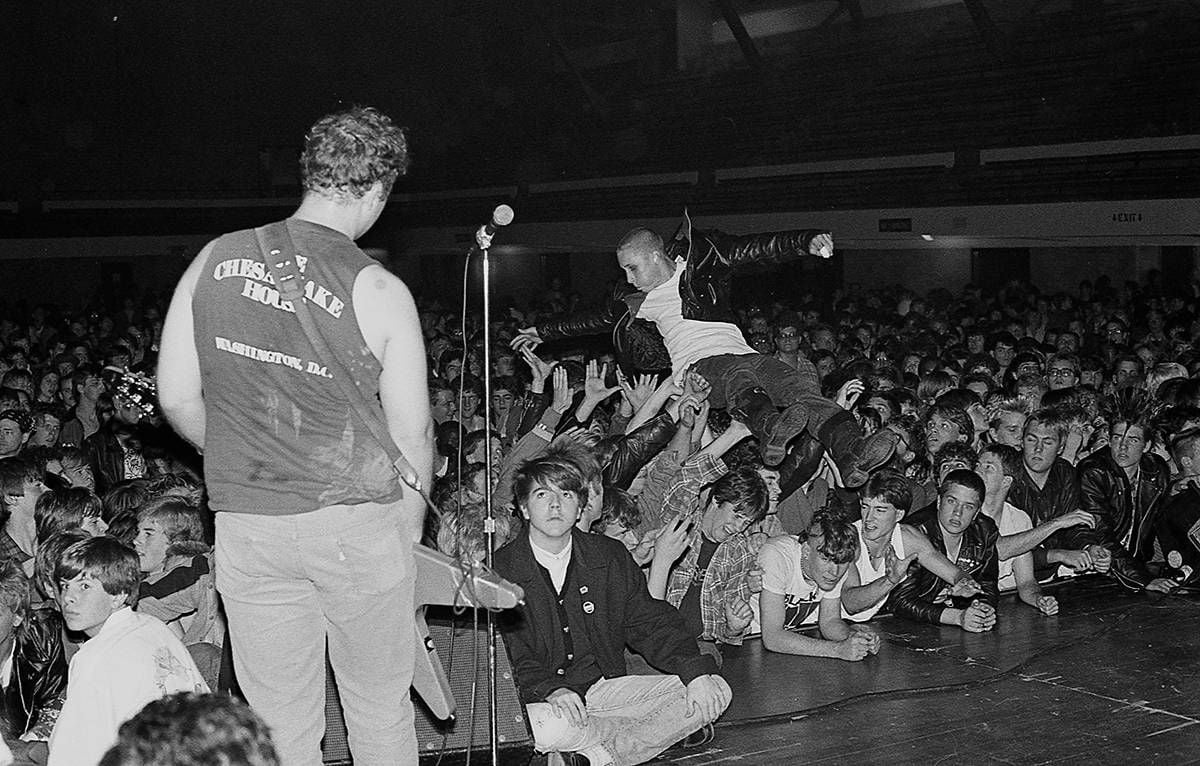 Hüsker Dü performs while a young person in a leather jacket stage dives into the crowd.