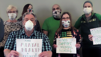 a group of people wearing masks and holding signs
