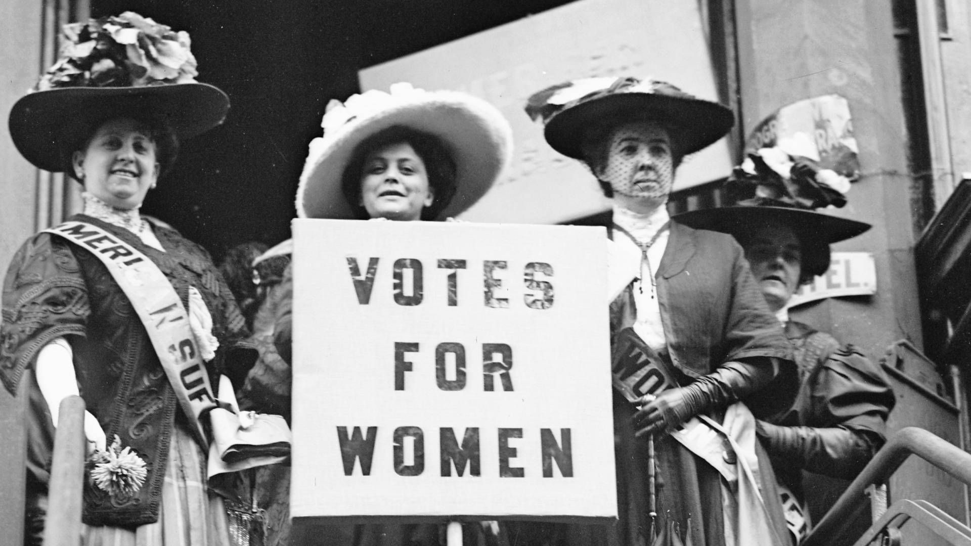a group of people wearing hats and holding a sign