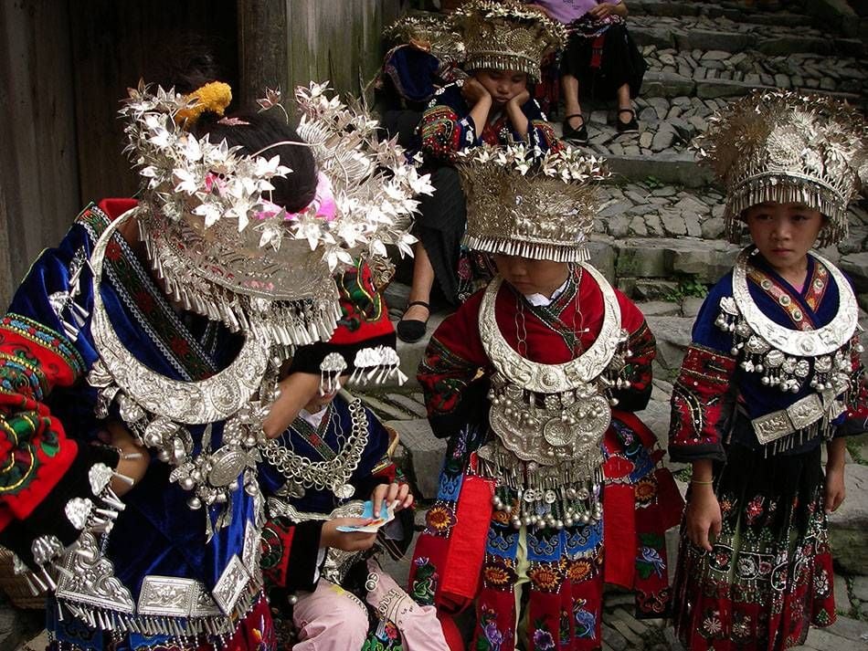 The Miao traditional dress is very similar to the Hmong dress. Both their outfits include layering fabrics, pleated skirts, similar headwear, silver jewelry and dangling adornments, as well as embroidery work. Note: These Miao outfits are more contemporary in style.