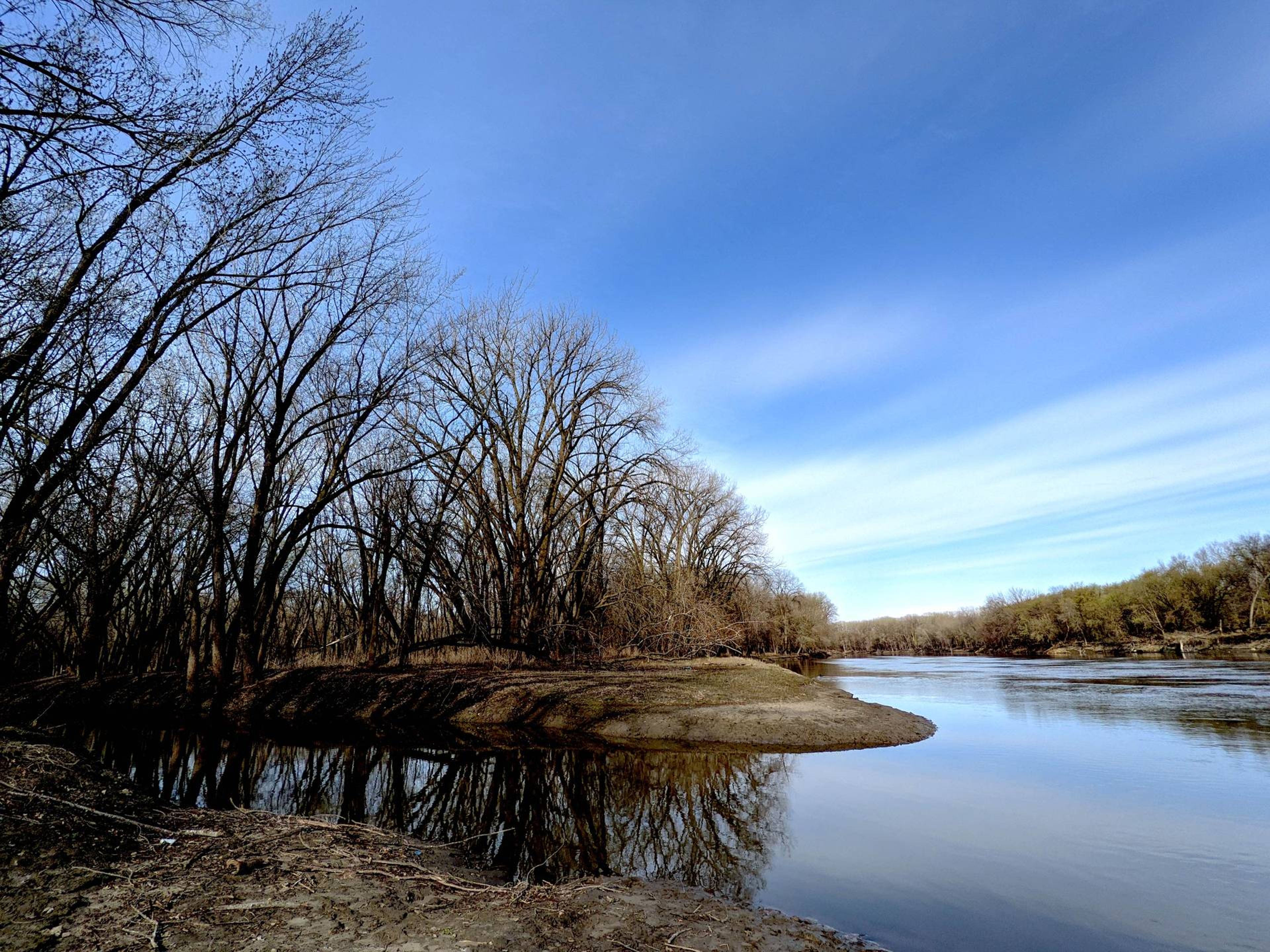 photo of a river, blue sky, no leaves on trees