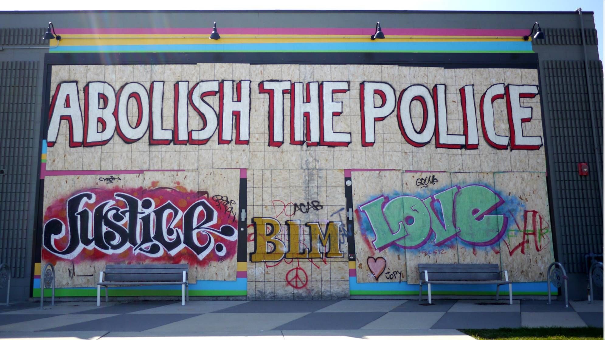 A mural with "Abolish the Police" painted in large block letters on plywood.
