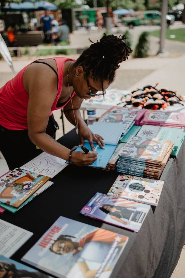 Crown Shepherd, who goes by the pen name Crown the Writer, signs copies of her children's book, Black Boy, Black Boy, which she hands out as a free gift to young and old readers at protests and demonstrations. | Photo courtesy of Crown Shepherd.