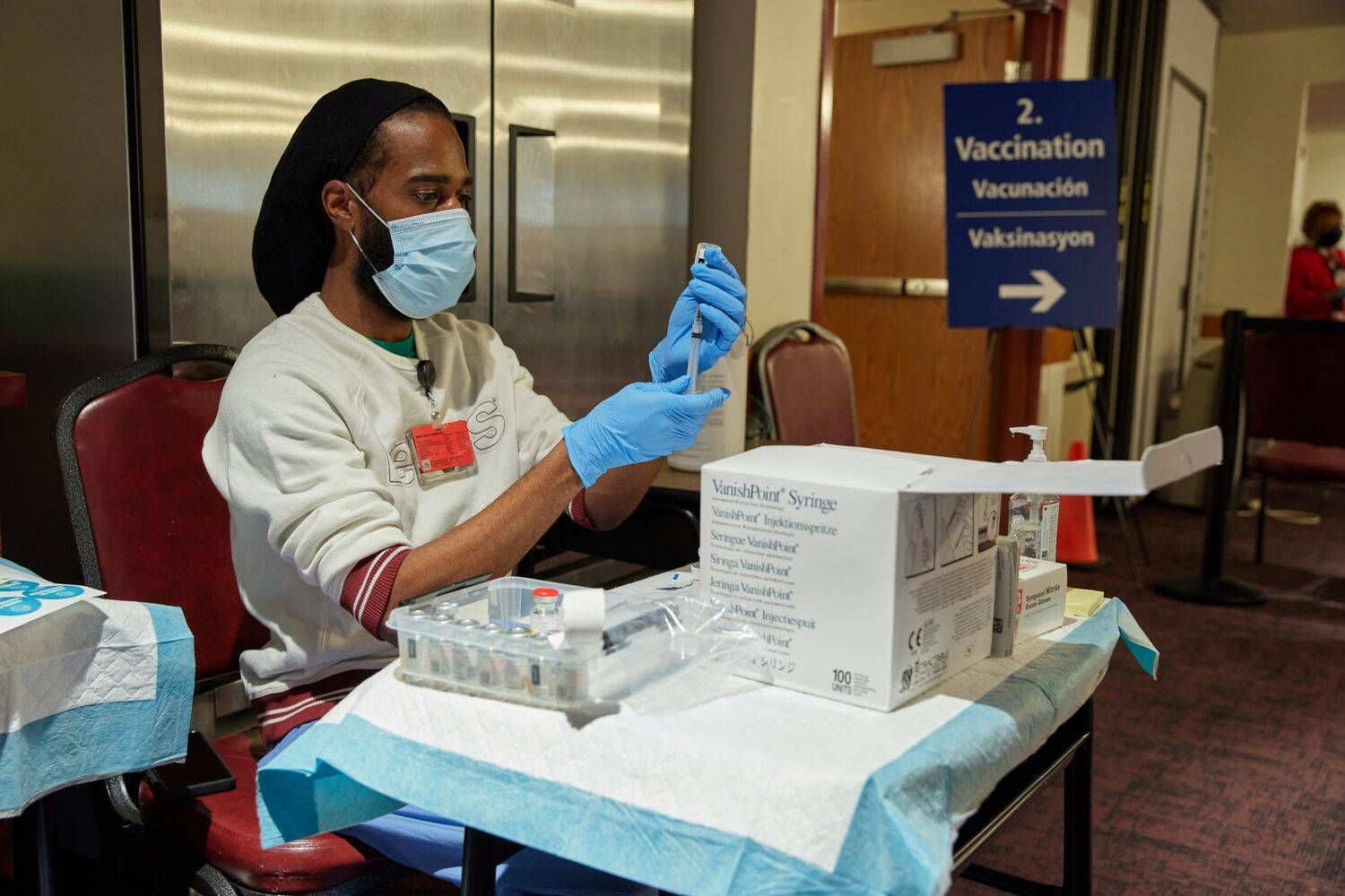 A medical worker at a vaccination site preps a vaccine into a syringe. 