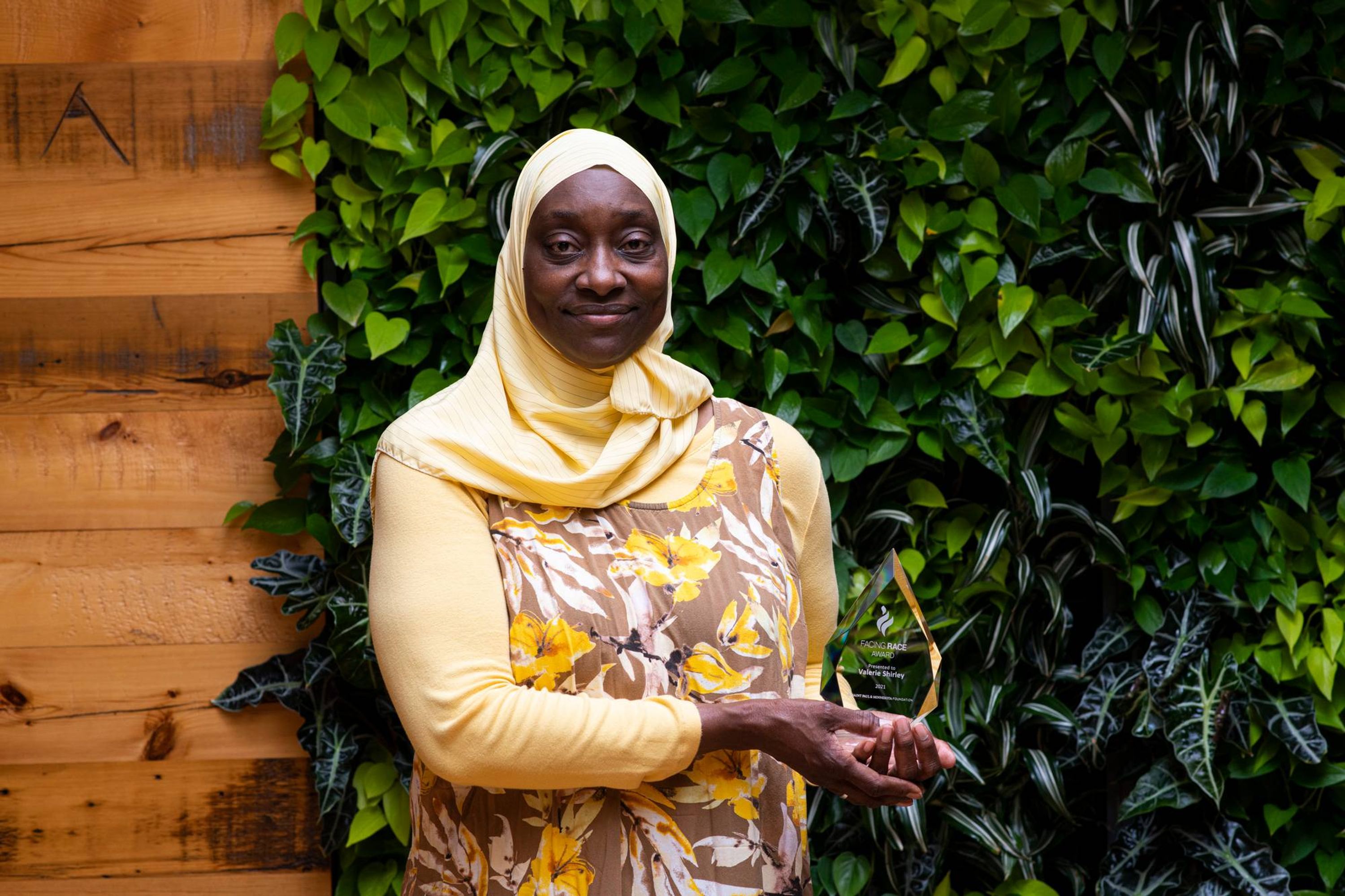 A smiling woman poses with an award.