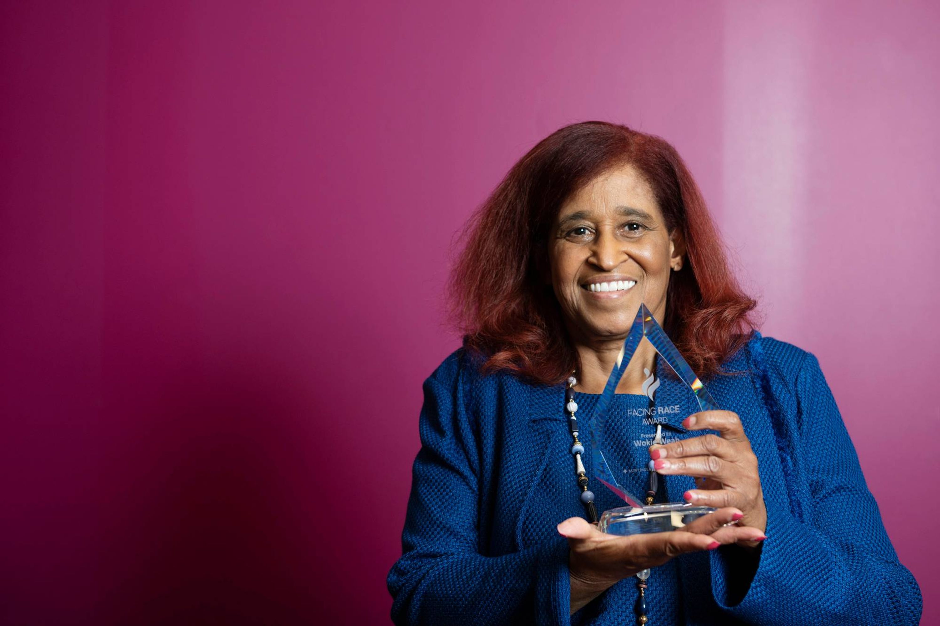 A smiling woman poses with an award.