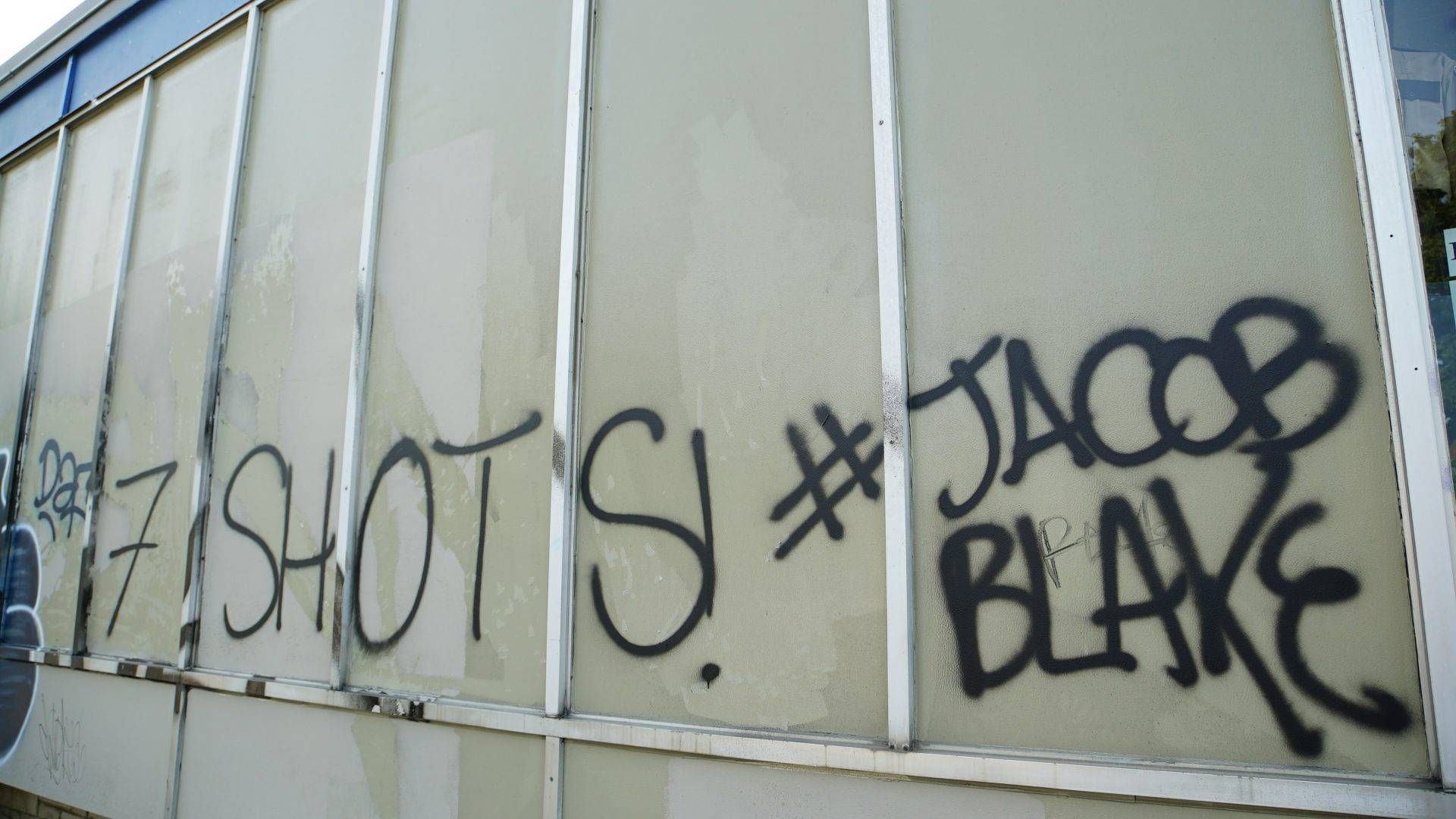 A building tagged with graffiti that reads, “7 Shots! #Jacob Blake”.