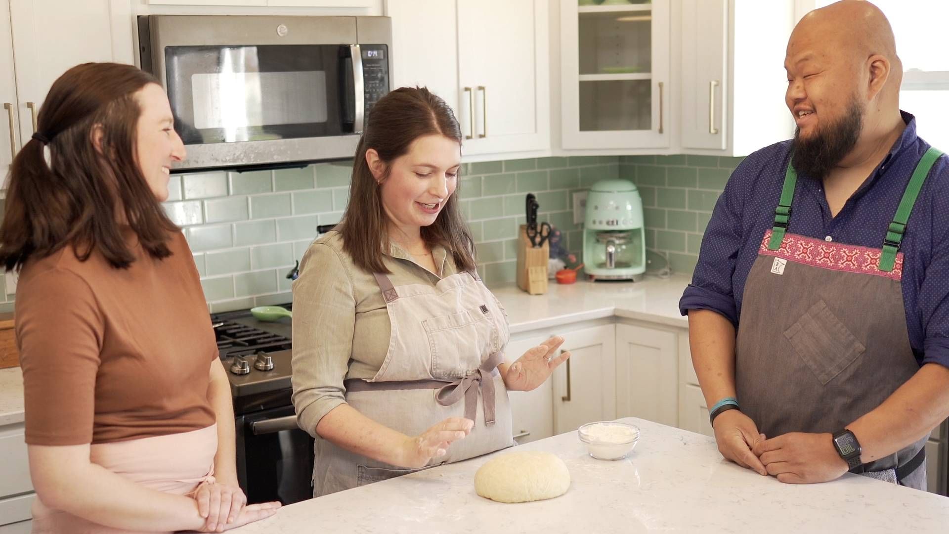 Samantha Kelly explains the elastic finish on the potica dough as Ashely Leonard and Yia Vang look on.