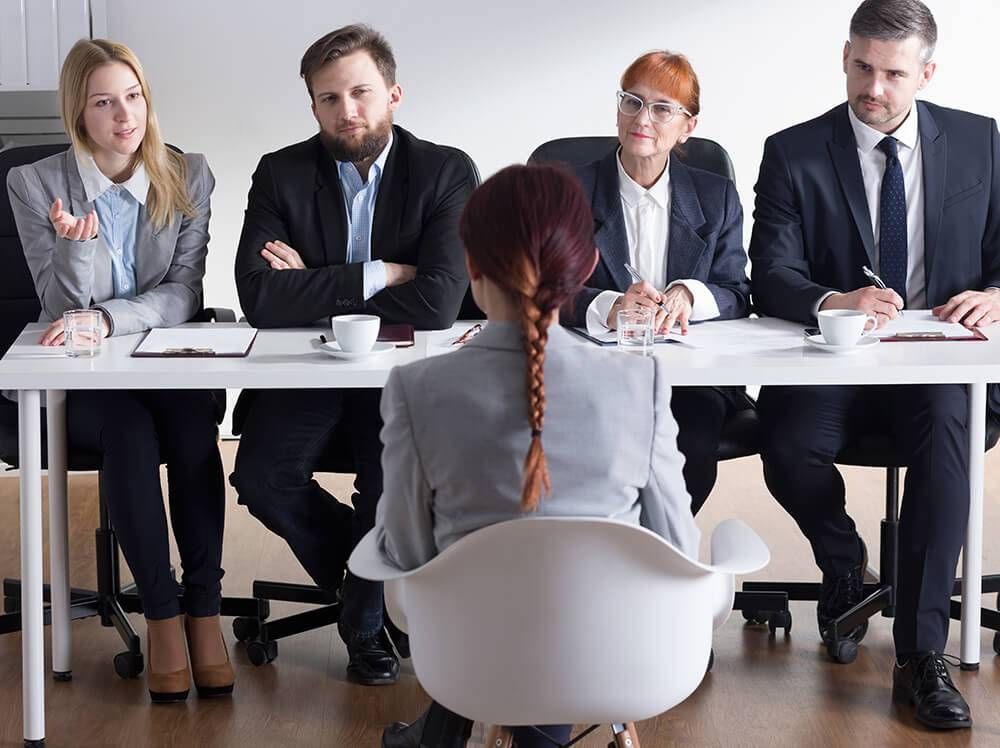 A young female job applicant is addressed by a panel of employers. Rewire PBS Work Interview