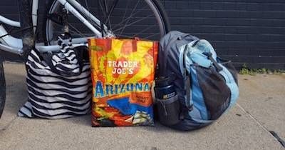 Two totes and a backpack next to a bicycle. Car-Free pbs rewire