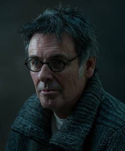 A photograph of filmmaker Michael Kirk, wearing a gray sweater and glasses. Rewire PBS Our Future America's Great Divide