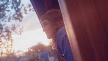 A photo of Katie Moritz leaning outside a window at sunset.
