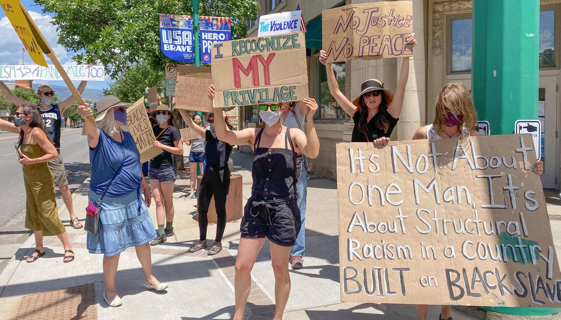 Protesters hold signs on a street corner in rural Colorado. Rewire PBS Our Future Activism Rural