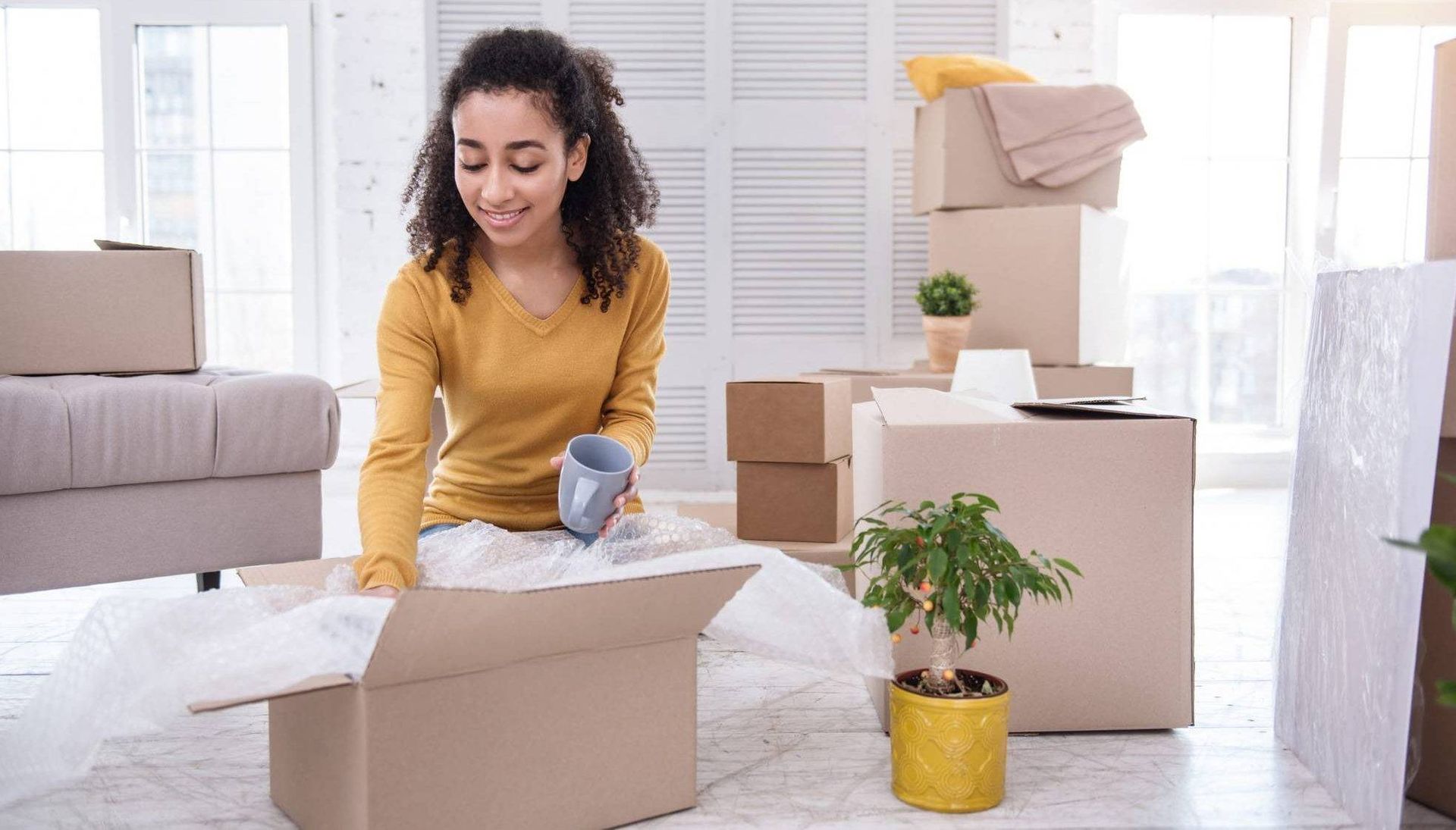 Young woman packing tea cup into box