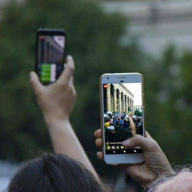 Hands holding cell phones at protest while recording the event