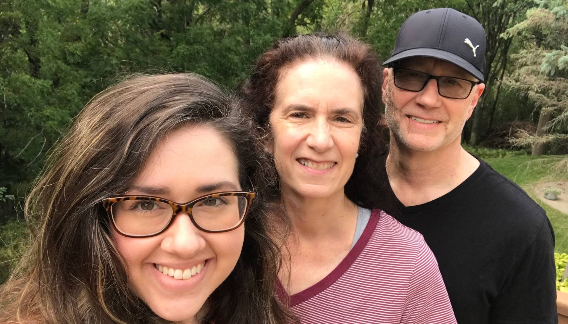 A young woman with her mother and father outdoors in the yard