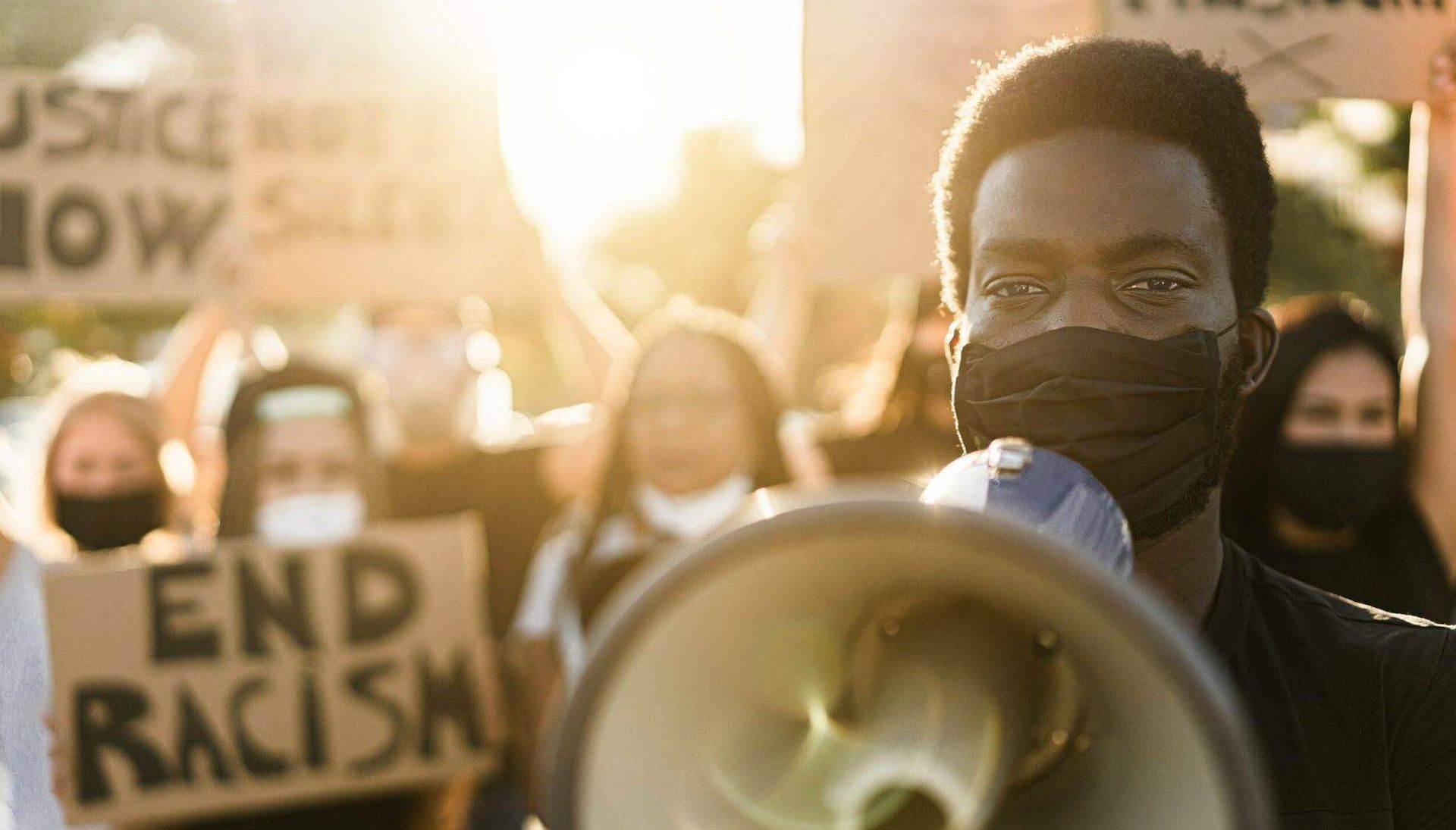 Protesters at a Black Lives Matter rally hold signs and megaphones in the street while wearing masks. Fighting for Black Lives Rewire PBS Our Future