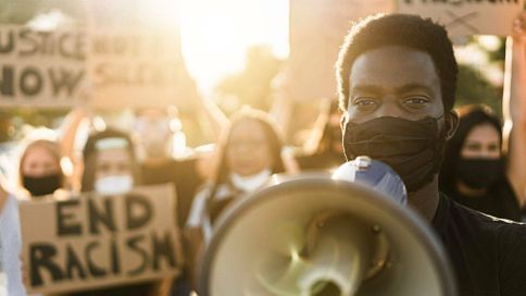Protesters at a Black Lives Matter rally hold signs and megaphones in the street while wearing masks. Fighting for Black Lives Rewire PBS Our Future