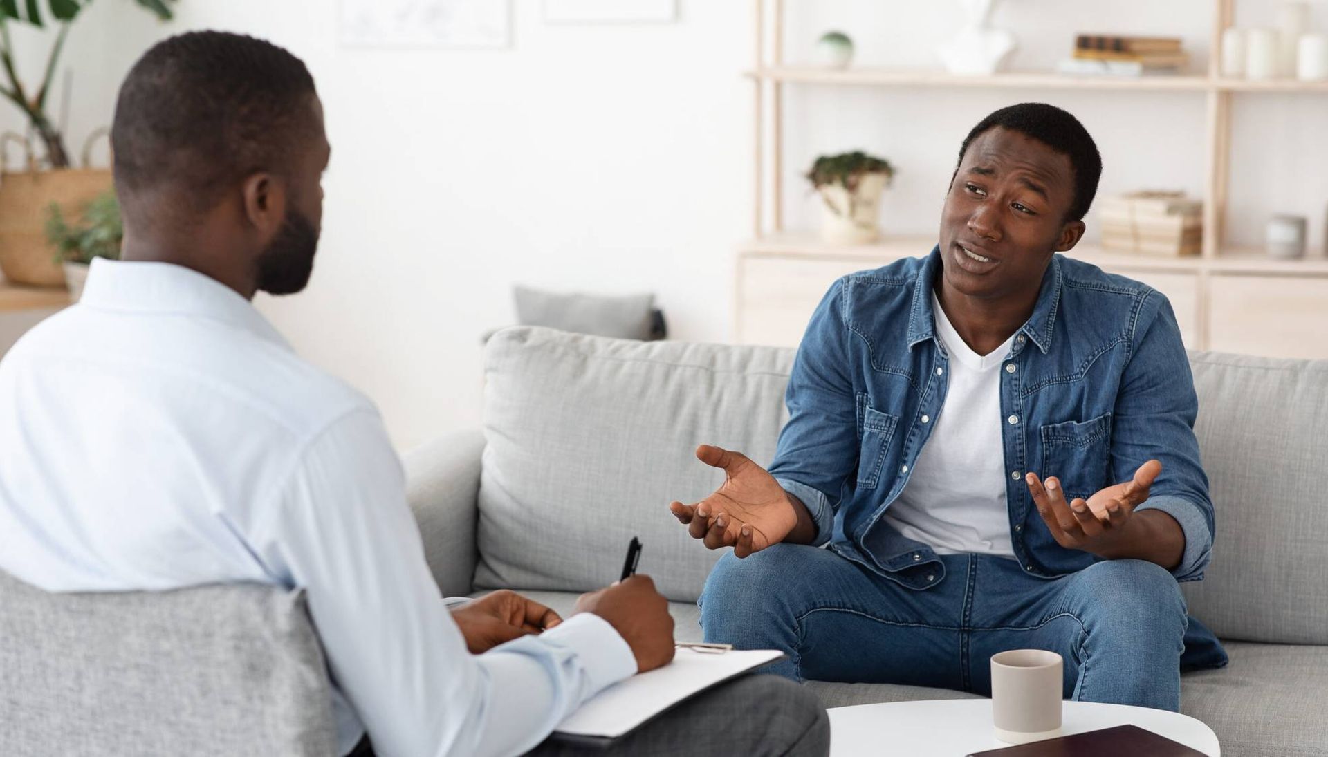 Stressed black man explaining his problems to psychologist at individual therapy session at office