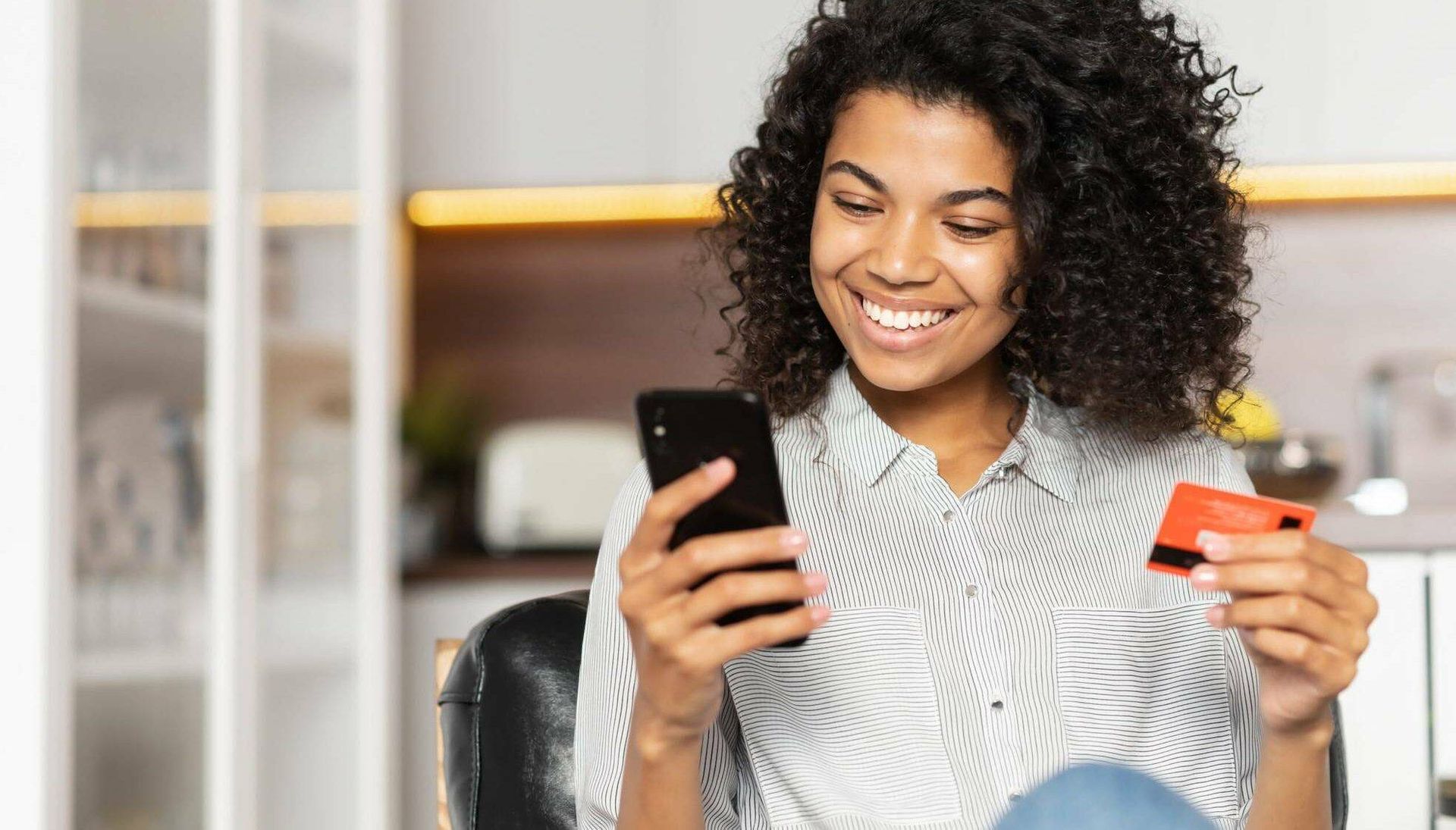 Young black woman holding smart phone and credit card while smiling