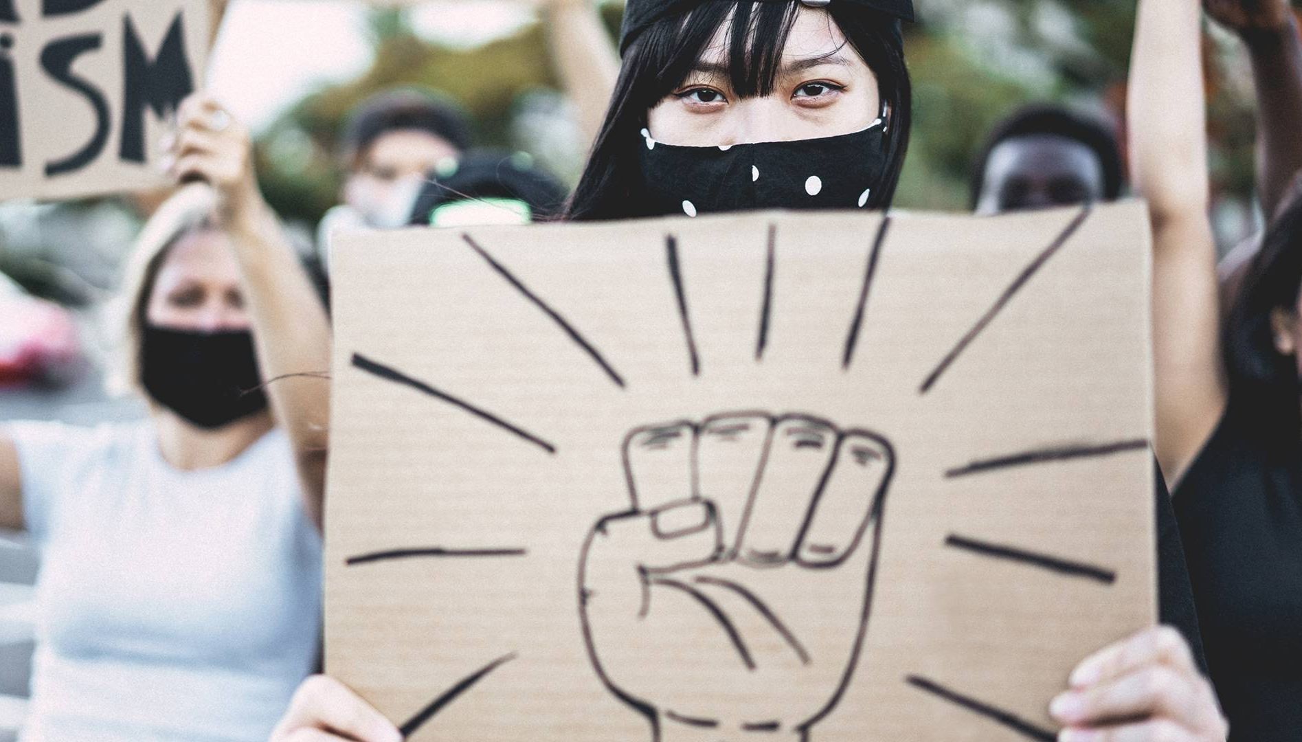 Asian girl wearing face mask while protest against racism on city street - Equal rights and demenstration concept - Focus on eyes