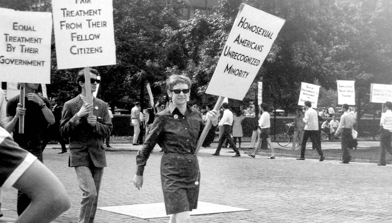 An old photograph of LGBTQ activists marching with signs. 'CURED' documentary, Rewire, PBS